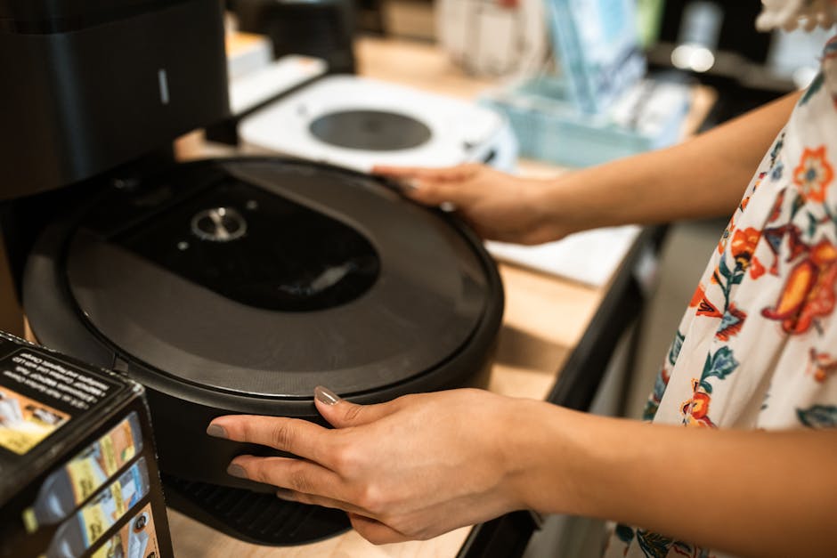 Žmogus parduotuvėje lygina dulkių siurblius, tikrina antgalius ir specifikacijas