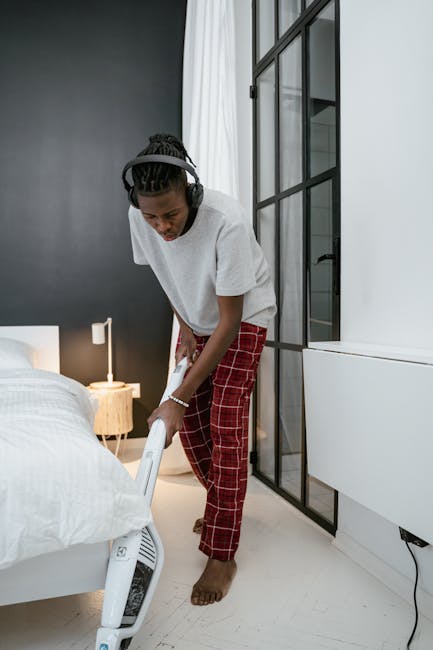 Žmogus siurbia miegamajame, kad sumažintų dulkių daleles ore